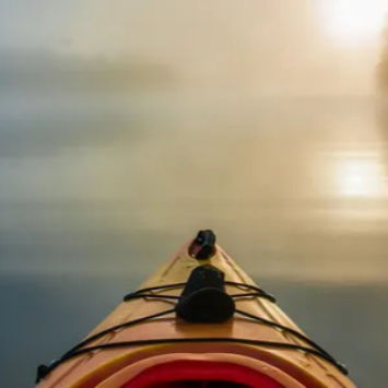 The bow of a kayak, looking out onto the river