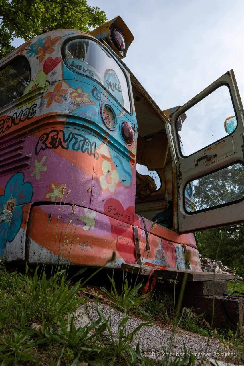 The back of a school bus painted in colorful, 1960s-style hippy artwork